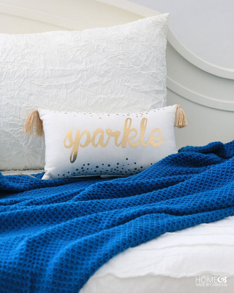 Decorative throw pillow with gold tassels and the word "sparkle"