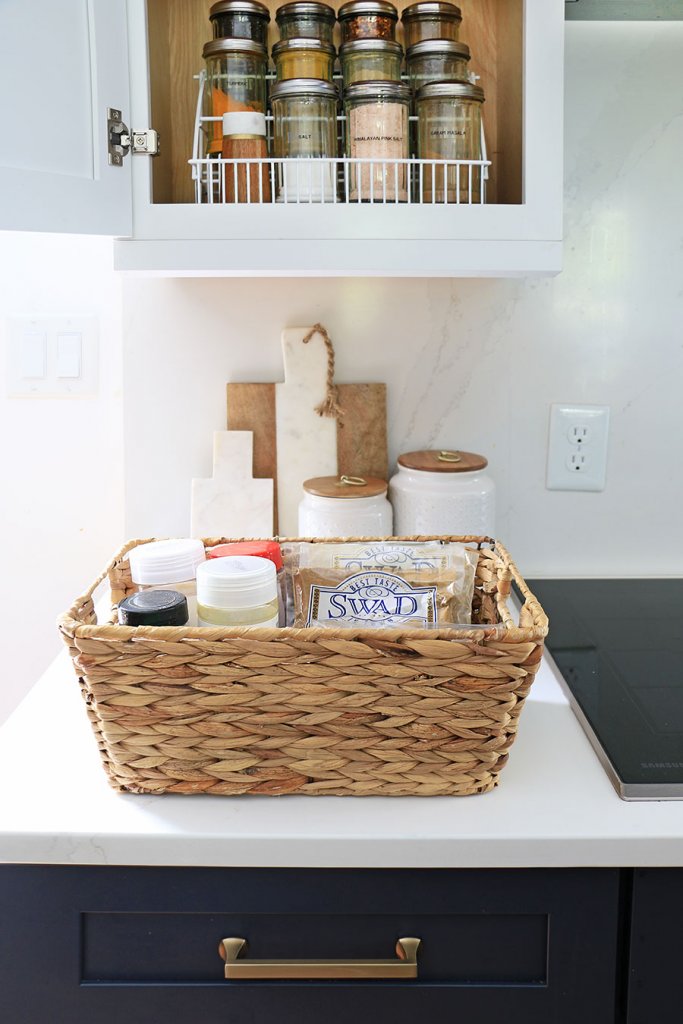 Woven basket containing condiments and spices on a kitchen worktop