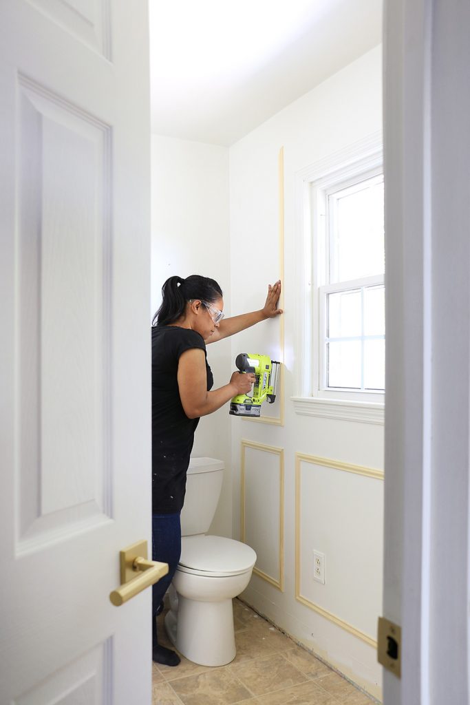 Woman installing chair moulding to a wall for architectural detail