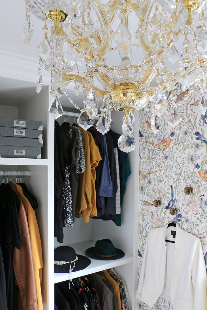 closet with clothes hanging and chandelier