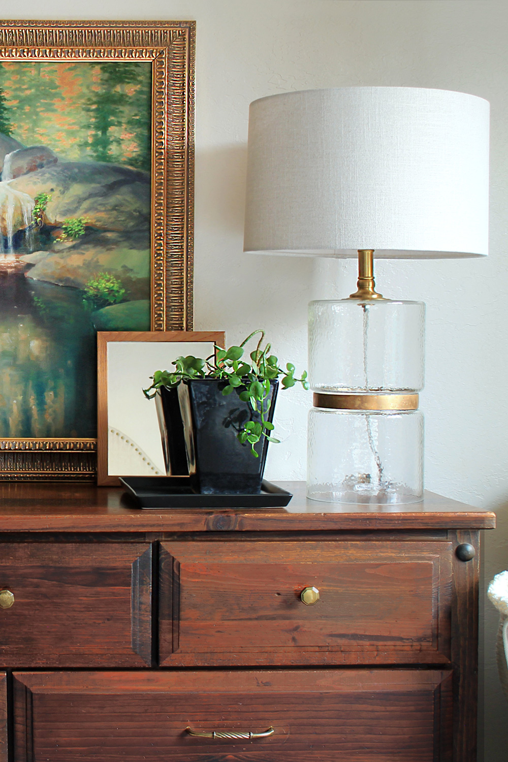 gold and glass table lamp on a dresser with accessories